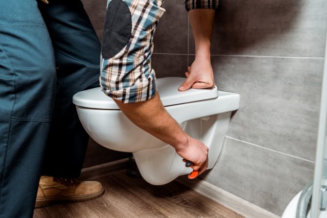 cropped view of installer standing near white toilet